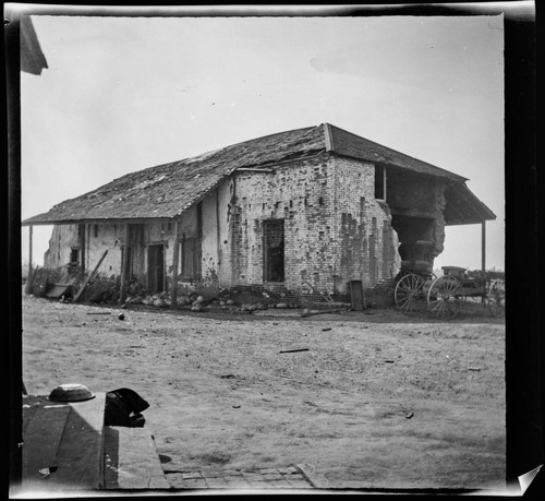 Dilapidated adobe with wagon next to it