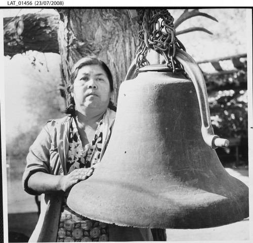 Mrs. Vivian Gomez at Tejon Ranch standing beside the bell from her village church