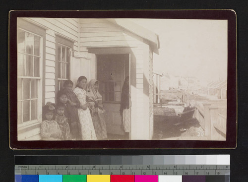 Seven girls, possibly native, standing by building