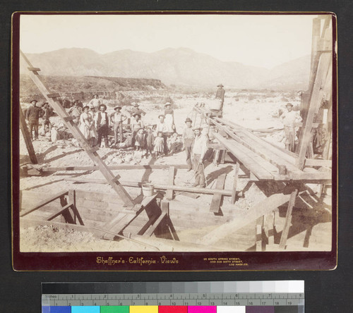 Men, women, and children at wooden structures in desert