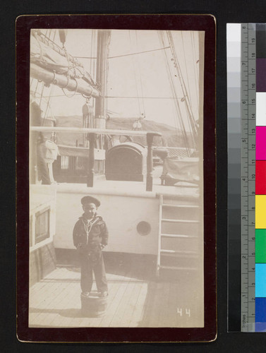 Small boy in sailor outfit on ship deck