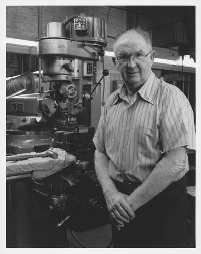 Fred O'Neil standing by a drill press in a machine shop