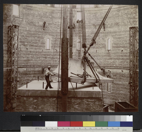 Construction worker at Yerkes Observatory guiding the second level of the piling onto the brick base for the 40-inch telescope