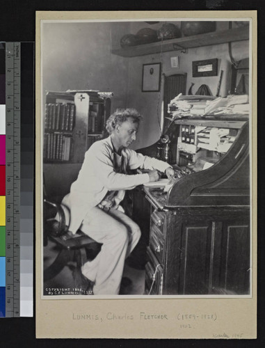 Charles F. Lummis sitting at his desk, writing