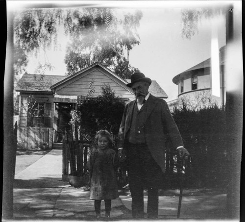 Man standing with a girl with a house behind them