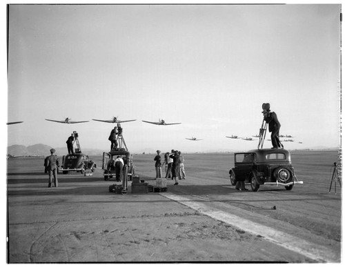 Men filming Army and Navy planes flying over a runway, Riverside. 1937