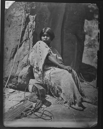 A young Southern Paiute woman with cradle-board next to her, Southeastern Nevada