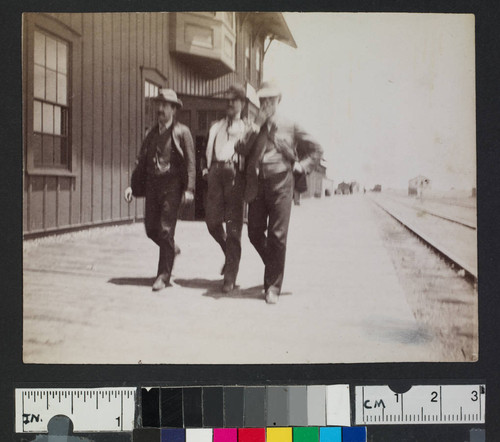 Men walking next to railroad tracks in a western town