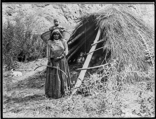 Woman holding bow and arrows and with child in carrying basket