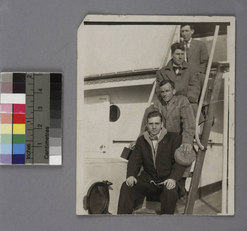 Edwin Powell Hubble and three (3) men sitting on a ladder aboard a trans-Atlantic ship