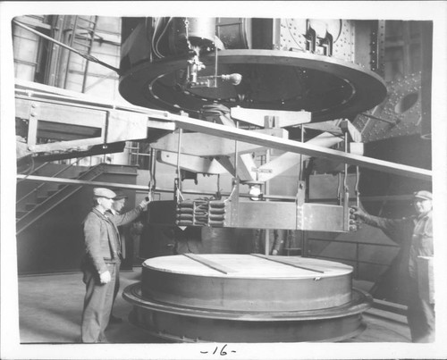 Three men lowering the lifting device onto the 100-inch mirror prior to returning it to the telescope, Mount Wilson Observatory