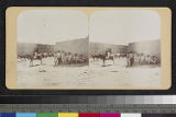 View of Acoma Pueblo, with men, children and horses in plaza