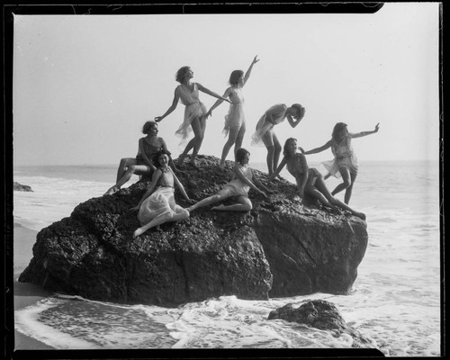 Dancers posing on a rock at the beach