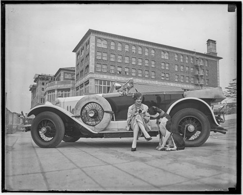 Woman and dog with car in front of the Club Casa del Mar, Santa Monica, California