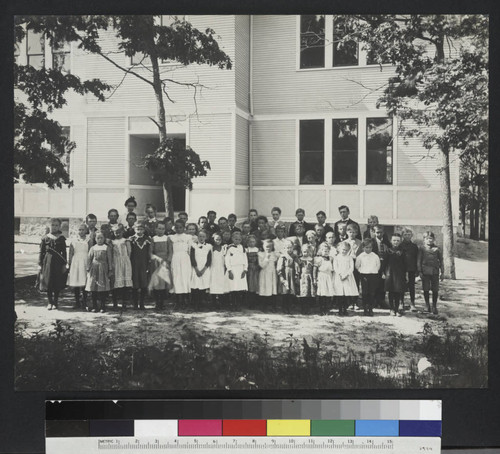 Schoolchildren and two teachers outside an unidentified building