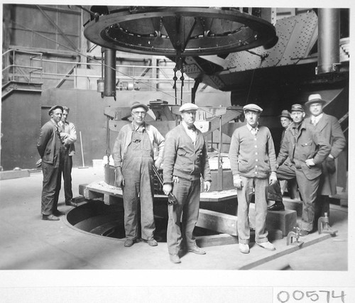 Eight men posed with the 100-inch mirror and its hoisting device, Mount Wilson Observatory