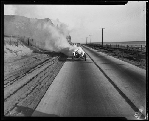 Auto racer driving "White Rocket" race car down coast highway, Santa Monica