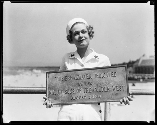 Woman holding dedication plaque for the Yacht Harbor Breakwater dedication, Santa Monica