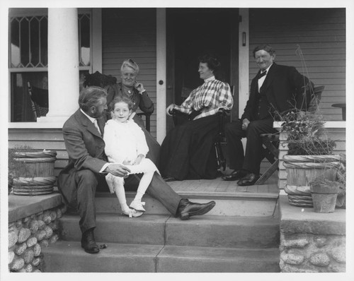 Ferdinand Ellerman, seated on the steps of a house with his family