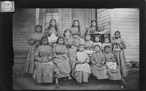 Group portrait of Modoc school girls and teacher showing work being done for the Philadelphia Exposition of 1876