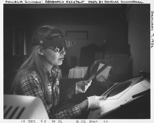 Pamela Gilman at a light box, with magnifying goggles