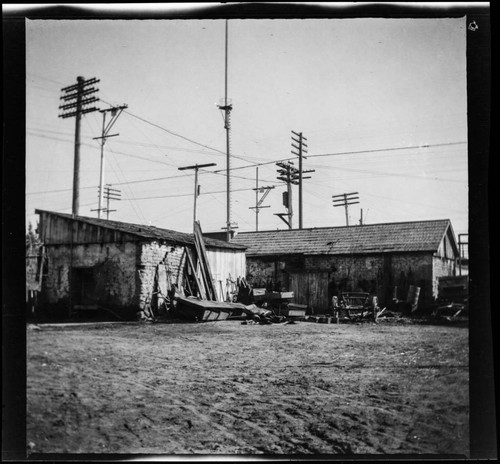 Dilapidated adobe buildings with piles of objects next to them in unidentified city