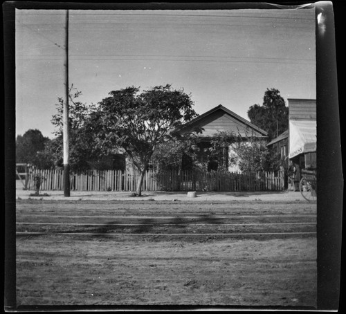 Unidentified house on city street with a harness shop at right