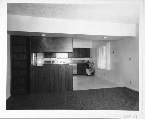 Interior of living room and kitchen of a new house on Mount Wilson, Hugh Couch attaching hardware to cabinets