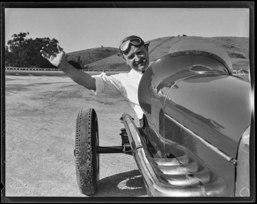 Race car driver Barney Oldfield waving from car at Legion Ascot Speedway, Los Angeles