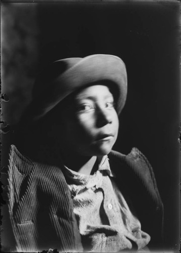 Portrait of Mountain Crow boy wearing felt hat and corduroy jacket