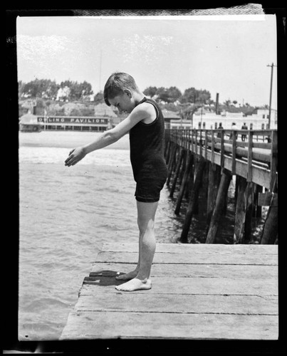 Boy in diving pose at end of North Beach Bath House Pier, Santa Monica