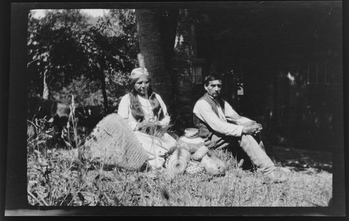 Mr. and Mrs. Whitmore under a tree with baskets - Karok