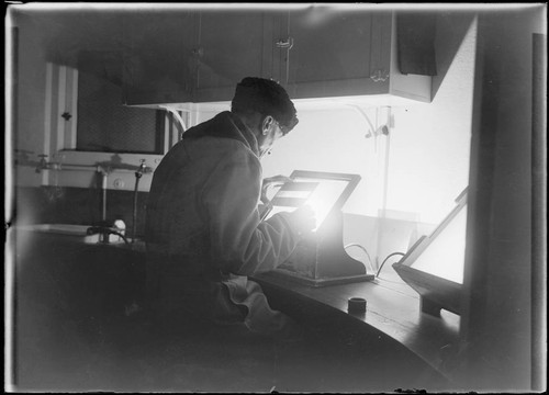 Scientist examining a plate on a light box at Mount Wilson Observatory