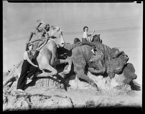 Women posing with hunter and bison sand sculpture, Santa Monica