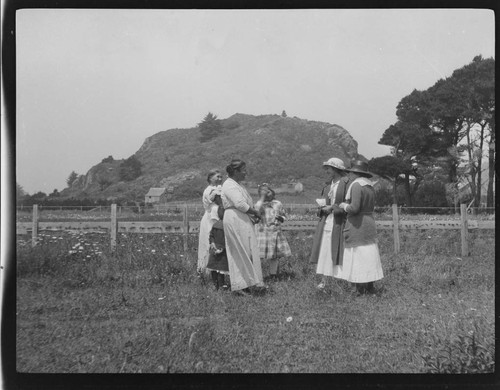 Grace Nicholson, far right, and unidentified white woman speaking to native women and children