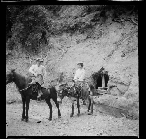 Two women riding burros in mountains