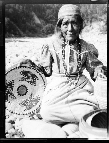 Mrs. Dolly Sanderson selling me [Grace Nicholson] her baskets on Klamath River below Red Camp. Karok