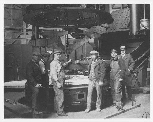 Six men posing with the hoisting device for moving the 100-inch mirror, Mount Wilson Observatory