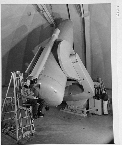 The 48-inch Schmidt camera, Palomar Observatory, with Bill Baum seated at the guidescope and Chuck Kearns standing at the control panel