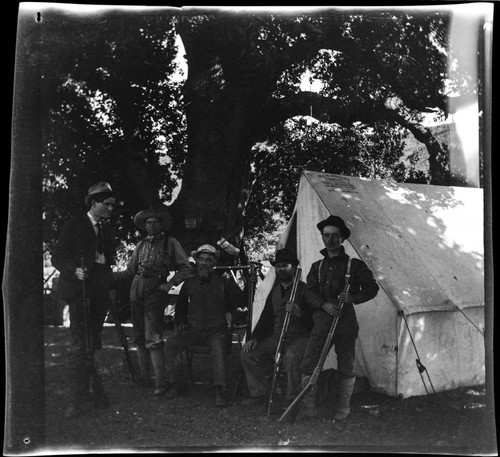 Group of men at camp with rifles