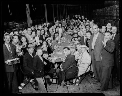 Crowd drinking mugs of beer at unidentified brewery