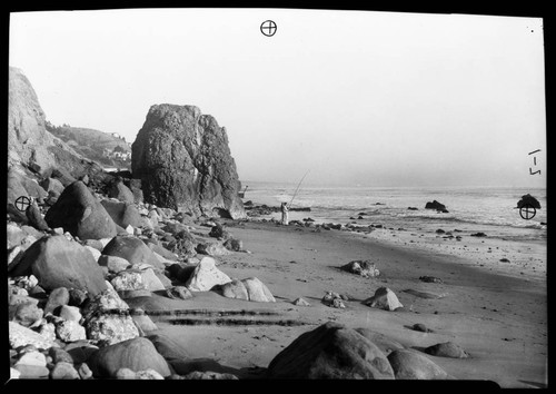 Castle Rock along highway with people fishing on the beach, Santa Monica