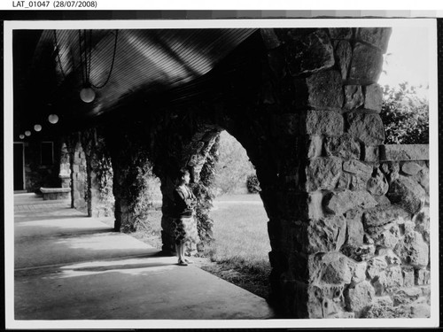 Young woman looking out through archway toward Vermejo lodge grounds