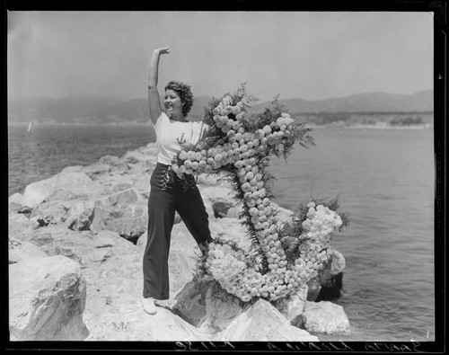 Woman posing with flower anchor on breakwater at the Yacht Harbor Breakwater Dedication, Santa Monica