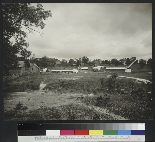 Outdoor scene of canvas tents, buildings, astronomy instruments and a telescope