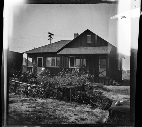 Unidentified house with two women and vegetable garden