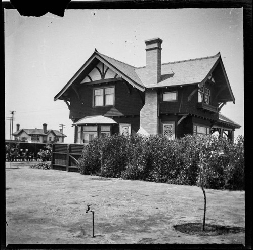 Unidentified two-story house with large lawn and new trees, back view