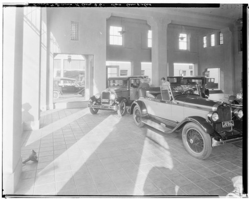 Automobile showroom with a roadster and a sedan. 1927