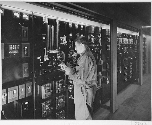 Unidentified man examining the breaker panel for the 200-inch telescope, Palomar Observatory