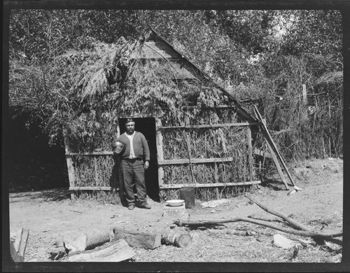 William Benson in front of summer brush house